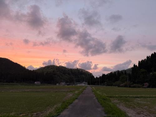 a dirt road in a field with a cloudy sky at Auberge eaufeu in Komatsu