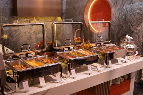 a buffet line with trays of food on a counter at Aurora Oriental Hotel in Hanoi