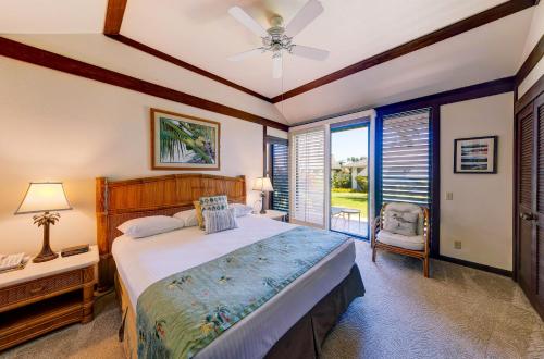 a bedroom with a bed and a table and a window at Kiahuna Plantation Resort Kauai by OUTRIGGER in Koloa