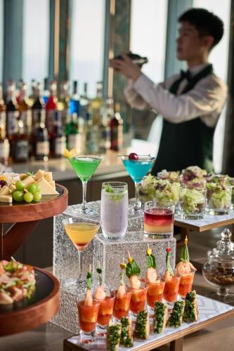 a man standing in front of a buffet with drinks at MaxX by Steigenberger Harbour-view Qingdao in Qingdao
