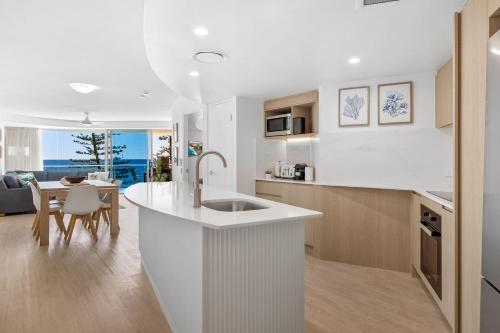 a kitchen with a white counter and a dining room at Sirocco 506 in Mooloolaba