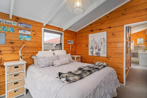 a bedroom with a bed in a room with wooden walls at Hosts on the Coast Cookies Cupboard in Pauanui