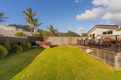a backyard of a home with a fence and grass at Hosts on the Coast Cookies Cupboard in Pauanui