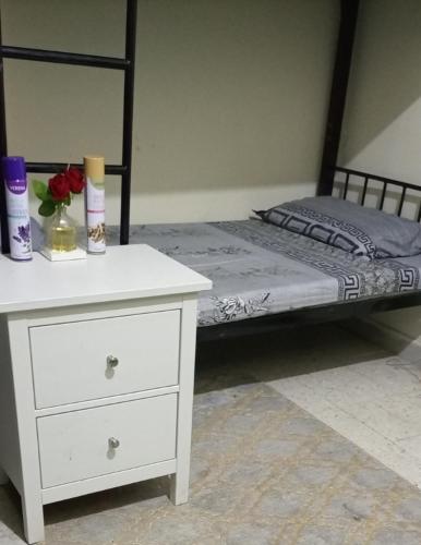 a bedroom with a bed and a white dresser with a drawer at ABD Cottages in Abu Dhabi