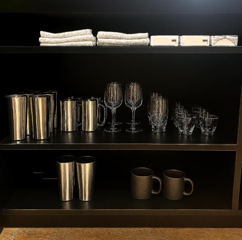 a shelf with wine glasses and mugs on it at Villa Moriyoshi in Tomakomai