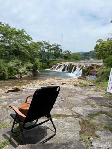 a chair sitting on a rock near a waterfall at Auberge eaufeu in Komatsu