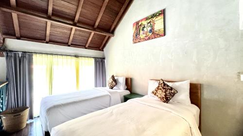 two beds in a room with a window at The Reward Villas Kerobokan in Seminyak