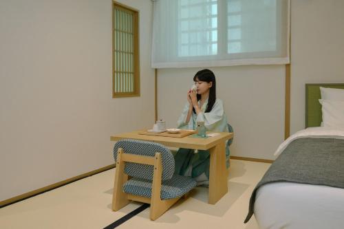 a woman sitting at a table in a hotel room at Aank Ryokan Hotel Songtan in Pyeongtaek
