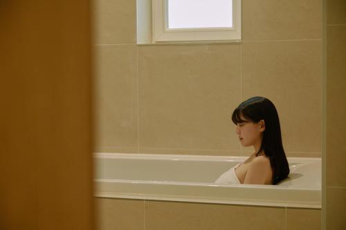 a woman is sitting in a bath tub at Aank Ryokan Hotel Songtan in Pyeongtaek