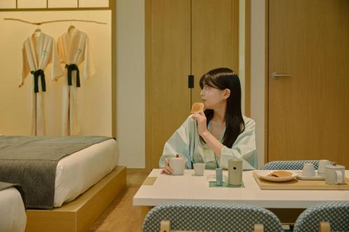a woman sitting at a table eating a doughnut at Aank Ryokan Hotel Songtan in Pyeongtaek