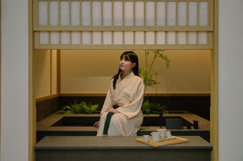 a woman in a kimono sitting on a counter at Aank Ryokan Hotel Songtan in Pyeongtaek