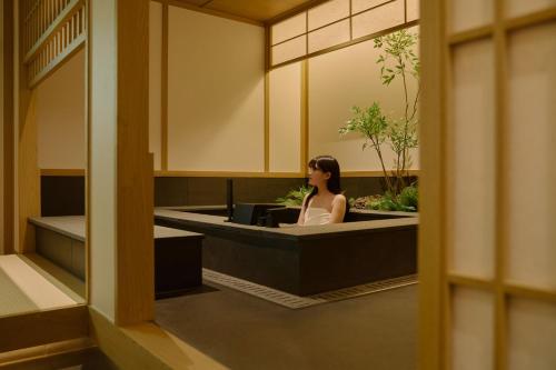 a woman sitting at a desk in a lobby at Aank Ryokan Hotel Songtan in Pyeongtaek