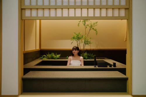 a woman sitting in a sink in a bathroom at Aank Ryokan Hotel Songtan in Pyeongtaek