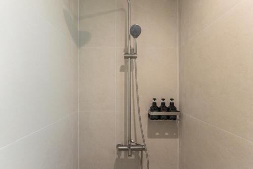 a shower with a glass door with bottles on a shelf at Aank Ryokan Hotel Songtan in Pyeongtaek