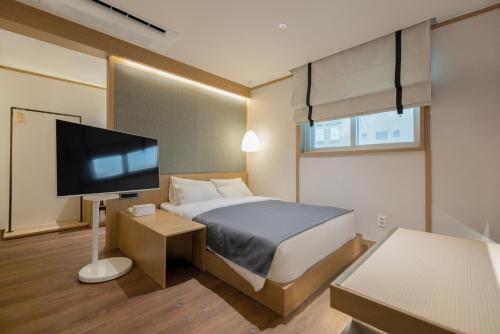 a bedroom with a bed and a flat screen tv at Aank Ryokan Hotel Songtan in Pyeongtaek