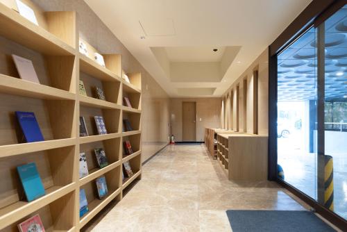 a library with wooden shelves with books at Aank Ryokan Hotel Songtan in Pyeongtaek