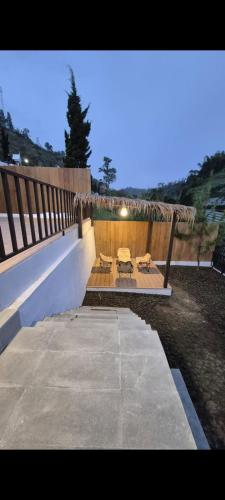 a patio with two tables and chairs and a fence at Mahkota Sangkuriang Bandung in Bandung