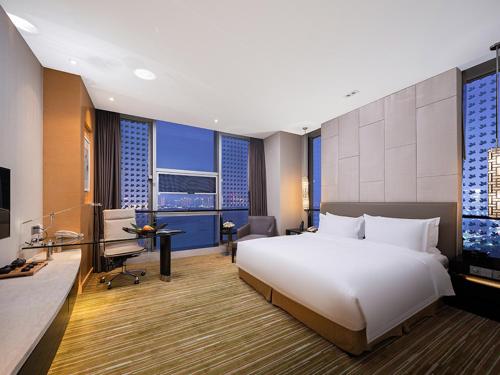 a bedroom with a large white bed and a desk at Holiday Inn Nanchang Riverside by IHG in Nanchang