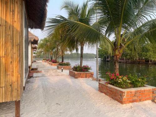 a walkway with palm trees and a body of water at Nov Koh Kong Resort in Phumĭ Srê Thmei