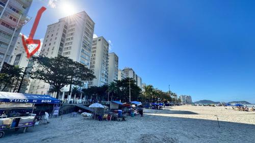 Una playa con edificios, mesas y sillas. en Suíte 300 Pitangueiras - na quadra da praia, en Guarujá