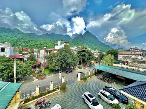 a city with cars parked in a parking lot with mountains at Loop Central Stay Tour & Motorbike Rental in Ha Giang