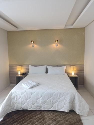 グァナンビにあるHotel Sabrinaのベッドルーム1室(白いベッド1台、2つの照明付)