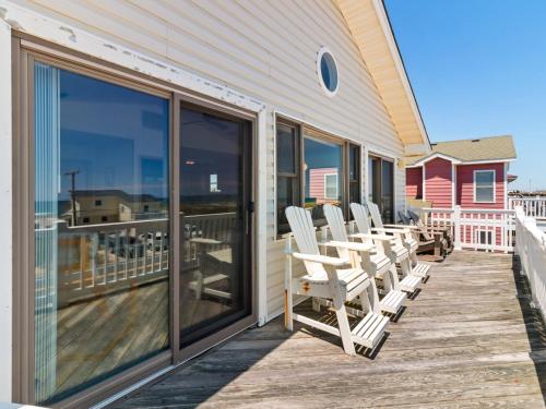 a deck with rocking chairs on the side of a house at 4070 - Sea Spray in Kitty Hawk
