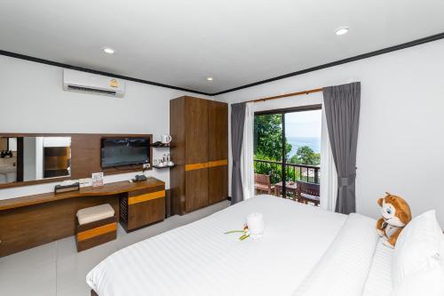 a bedroom with a large white bed and a television at Secret Cliff Resort & Restaurant - SHA Plus in Karon Beach