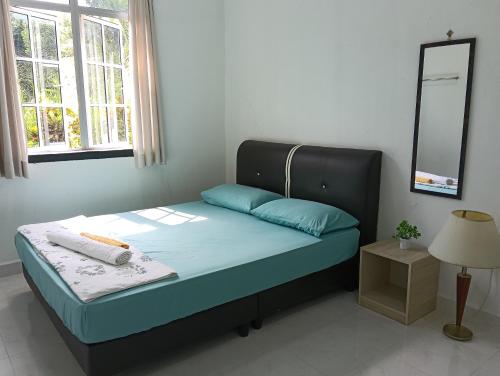 a bedroom with a bed with a mirror and a lamp at Rossy Homestay in Kuah