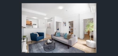 a living room with a couch and two blue chairs at East Perth Apartment Suites with Parking in Perth