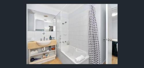 a white bathroom with a sink and a shower at East Perth Apartment Suites with Parking in Perth