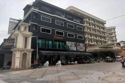 a large black building with dogs sitting in front of it at Golden Star Pattaya in Ban Nong Chaeng