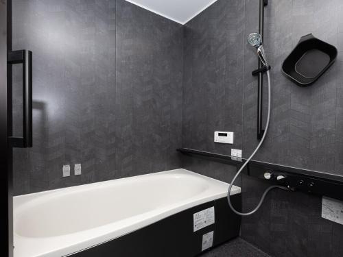 eine Badewanne in einem Badezimmer mit Dusche in der Unterkunft Plus RIVERPOOL 埼玉ちちぶ in Minano