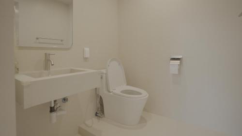 a white bathroom with a toilet and a sink at Island Stay in Jeju