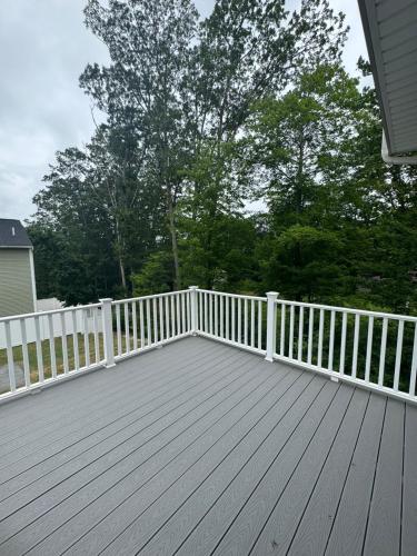 a wooden deck with a white fence and trees at Elegant 3BR Home in Worcester in Worcester