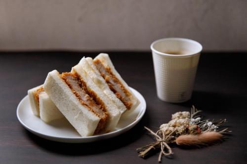 two sandwiches on a plate next to a cup of coffee at Uwajima Oriental Hotel in Uwajima