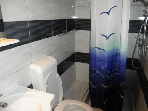 a bathroom with a toilet and a shower with birds on the shower curtain at Apartment Rosse in Split