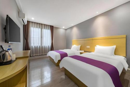 a hotel room with two beds and a television at Ying Feng Yuan Hotel in Guangzhou