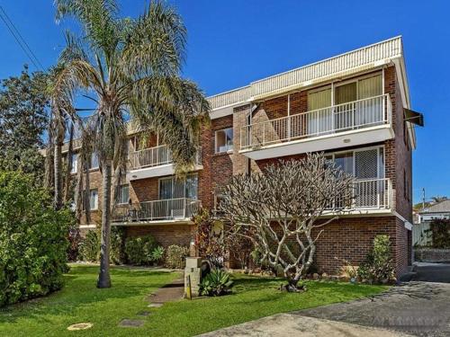 a brick apartment building with a balcony and palm trees at Cul-de-Sac Cove, Unit 4 in The Entrance