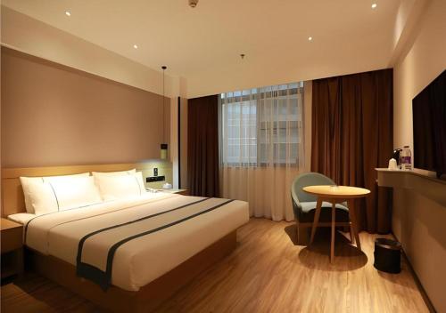 a hotel room with a large bed and a table at City Comfort Inn Qingyuan City Plaza Hefu Dongcheng in Qingyuan