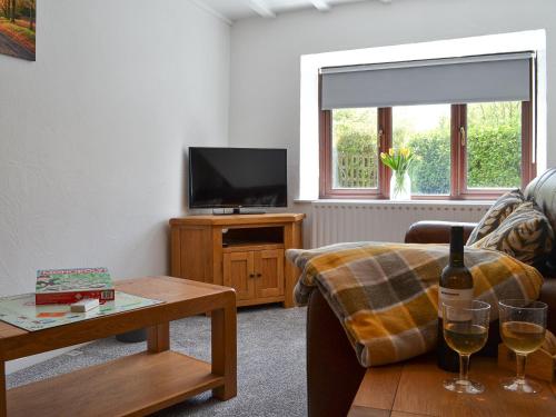 un soggiorno con un divano e un tavolo con bicchieri da vino di Willow Cottage a Woolfardisworthy