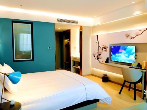 une chambre avec un lit, un bureau et une télévision dans l'établissement Magnotel Hotel Xuzhou Xinxin Yurun Plaza Zhongwu Road, 