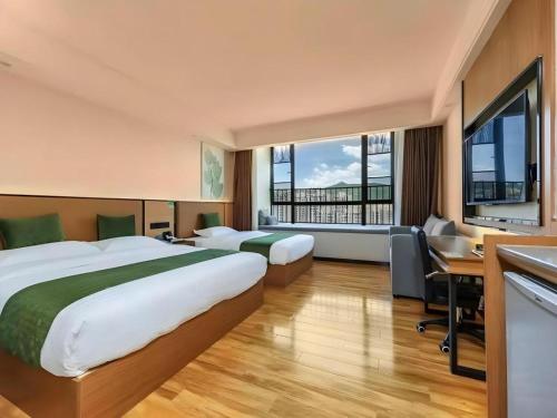 a hotel room with two beds and a desk at GreenTree Inn Tangshan Nanhu International Exhibition Center in Tangshan