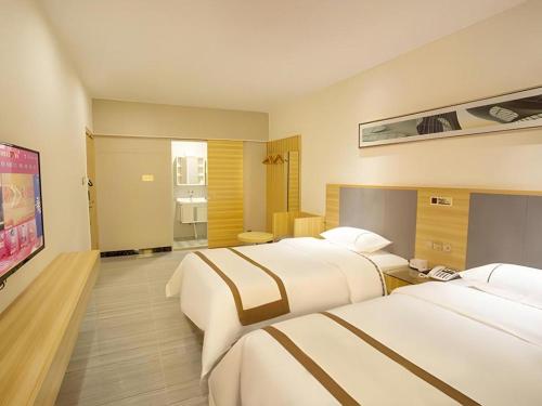 una camera d'albergo con due letti e una TV a schermo piatto di JTOUR Inn Zhanjiang Poly Yuandian Plaza a Zhanjiang