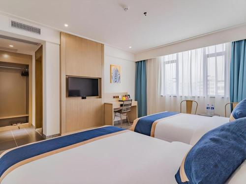 a hotel room with two beds and a flat screen tv at Borrman Hotel Huizhou West Lake Shuidong Street in Huizhou