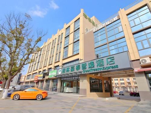 a orange car parked in front of a building at GreenTree Inn Express Zhangjiagang Hexing Town Shazhou Professional Institue of Technology in Qiwei