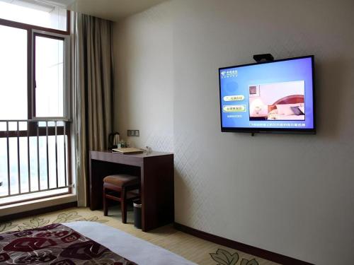 a hotel room with a flat screen tv on the wall at GreenTree Inn Anqing Yingbin Dong Road High-Speed Railway Station in Anqing