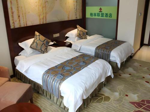 a hotel room with three beds and a couch at GreenTree Inn Anqing Yingbin Dong Road High-Speed Railway Station in Anqing