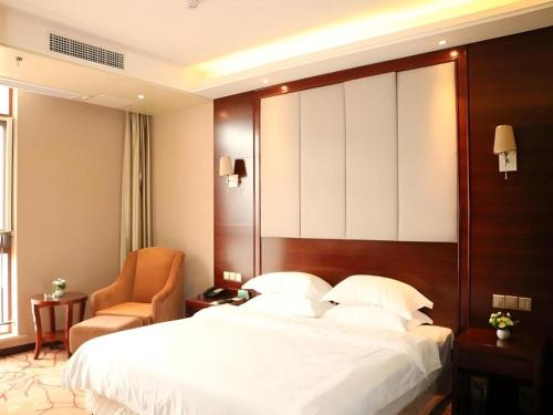 a hotel room with a large bed and a chair at GreenTree Inn Anqing Yingbin Dong Road High-Speed Railway Station in Anqing