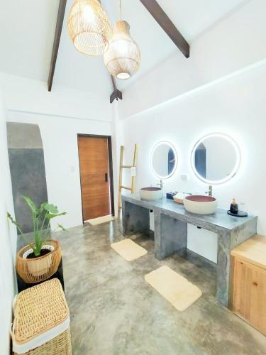 a bathroom with two sinks and two mirrors at Villa Cali Siargao in General Luna
